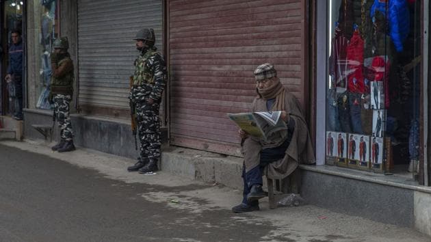 A Kashmiri shopkeeper read newspapers outside his shop as Indian Paramilitary soldiers stand guard in central Srinagar, Indian controlled Kashmir, Thursday, Feb. 20, 2020.(AP photo for representation)