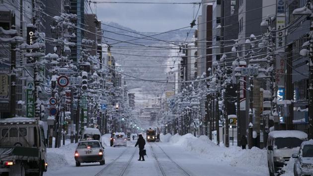 A man walks across an icy street in Sapporo. The lack of snow however — and then an abundance of it — is also a sign that the local climate is changing, which has researchers in the area watching the weather very closely. (Jae C. Hong / AP)