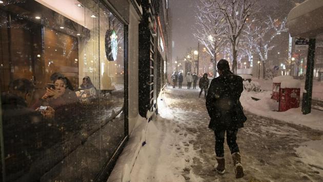 A man walks through a snow storm past a coffee shop in Sapporo. In fact, it was difficult to keep the snow festival going this year. Trucks had to bring in snow from everywhere to keep the festival going, an event that attracts hundreds of thousands of tourists. The city’s 40-year-old ski marathon event was cancelled due to a lack of snow. (Jae C. Hong / AP)