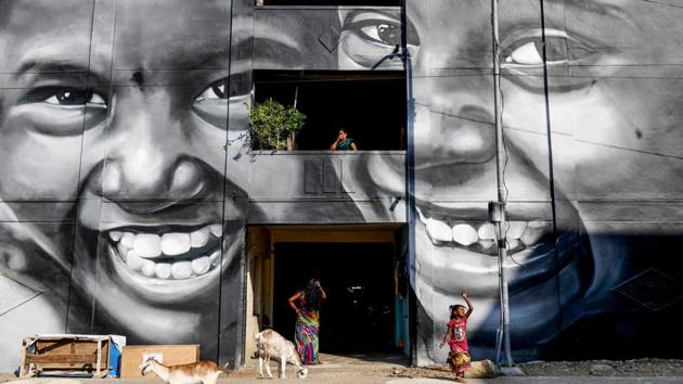 Residents walk past a mural painted on a building at a slum clearance board residential community in Chennai, Tamil Nadu. (Arun Sankar / AFP)