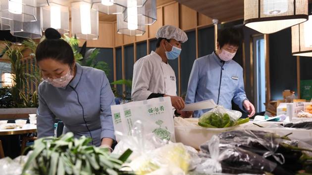 Some establishments have turned to selling fresh and frozen products directly to communities. In Yunhaiyao, a chain specialising in Yunnan cuisine, restaurant tables are piled with fresh vegetables instead of cooked dishes—ready to be packed and delivered to housing compounds. (Greg Baker / AFP)