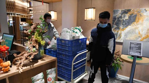 Workers hauling a cart loaded with vegetables at Yunhaiyao restaurant before delivering them. Yunhaiyao, which has more than 100 outlets in China, now bulk-buys groceries for residents near its stores as a new income stream. It has also rolled out a fresh line of prepared ingredients for customers cooped up at home. (Greg Baker / AFP)