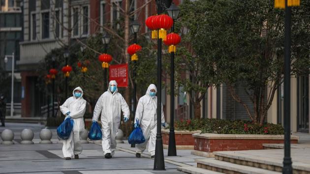 Community staff members out delivering food to residents in Wuhan. A survey by Peking and Tsinghua universities, covering around 1,000 small- and medium-sized enterprises, said about 85% of these firms could only survive up to three months on their cash reserves. (AFP)