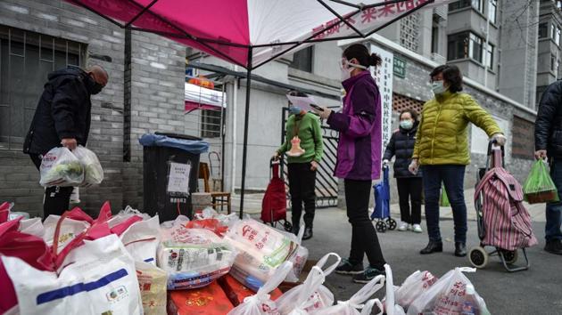 Residents collect food distributed by volunteers outside their home in Wuhan. The China Cuisine Association said in a report this month that the country’s restaurant industry saw 4.67 trillion yuan ($665 billion) in catering revenue last year, with earnings over the Lunar New Year break making up over 15%. With millions staying indoors this year, those holiday earnings have evaporated. (Chinatopix via AP)