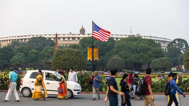 Pedestrians walk past an American flag flying from a post near Parliament House ahead of the arrival of U.S. President Donald Trump in New Delhi. (Bloomberg)