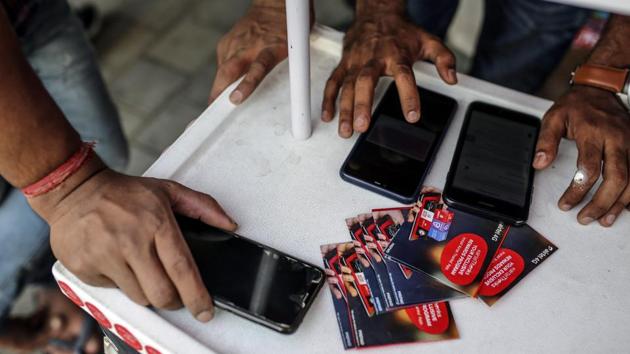 A customer is served at a stall selling SIM card packets outside a mobile phone store in Mumbai.(Bloomberg) A customer is served at a stall selling SIM card packets outside a mobile phone store in Mumbai.(Bloomberg)