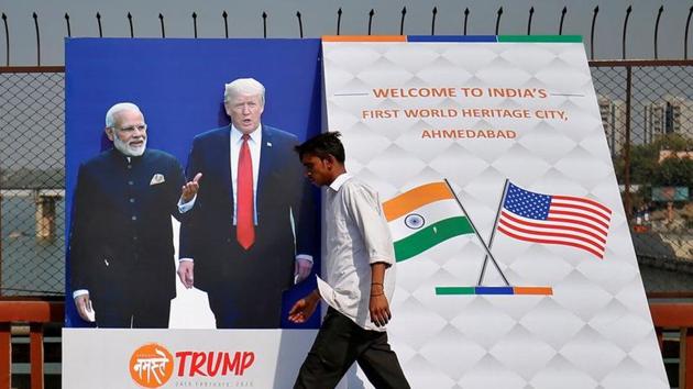 A man crosses a bridge past a hoarding with the images of U.S. President Donald Trump and India's Prime Minister Narendra Modi, ahead of Trump's visit, in Ahmedabad. (REUTERS)