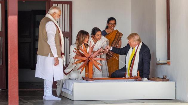 US President Donald Trump tries spinning on a traditional 'charkha' at Sabarmati Ashram in Ahmedabad on Monday.(PTI PHOTO.)