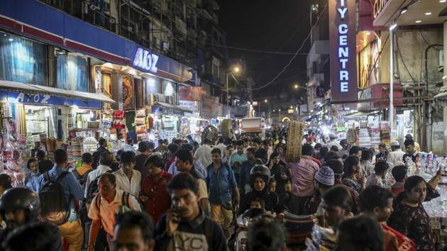 Pedestrians and shoppers walk past stores near Crawford market at night in Mumbai.(Bloomberg)