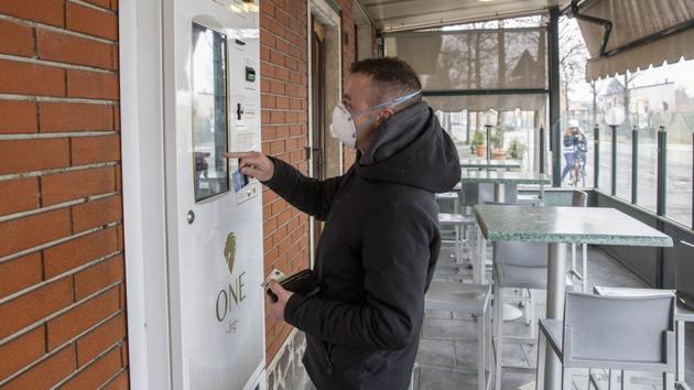 A customer, wearing a protective face mask, buys cigarettes from a vending machine in the town of Guardamiglio, Italy, which is currently the worst hit EU country from novel coronavirus. Feb. 25, 2020.(Bloomberg) A customer, wearing a protective face mask, buys cigarettes from a vending machine in the town of Guardamiglio, Italy, which is currently the worst hit EU country from novel coronavirus. Feb. 25, 2020.(Bloomberg)