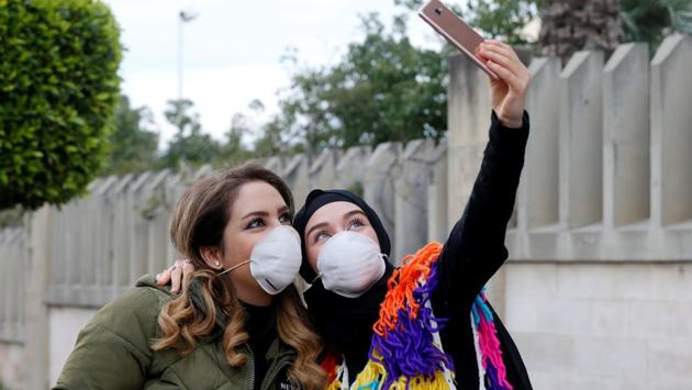 People wearing face masks take a picture with a mobile phone outside Rafik Hariri hospital, where Lebanon's first coronavirus case is being quarantined, in Beirut, Lebanon. (Mohamed Azakir / REUTERS)