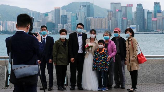 Newly-wed couple wear protective masks as they take wedding photos with family after marriage registration, following the outbreak of the new coronavirus, at Tsim Sha Tsui district in Hong Kong. (Tyrone Siu / REUTERS)