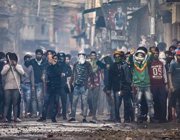 A mob armed with sticks — some of them covering their faces — can be seen during a clash in North-east Delhi on Tuesday.(Photo: PTI)