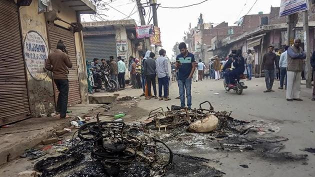 Passersby look at the charred remains of vehicles which were set ablaze by rioters during clashes over the new citizenship law, at Mustafabad area of East Delhi.(PTI)