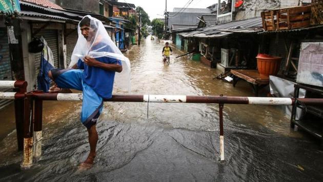 A man wearing a plastic sheet travels along a flooded street at Pondok Maharta residence, South Tangerang, near Jakarta, Indonesia. Torrential rain brought floods to Indonesia’s capital on Tuesday, paralysing large parts of the city as rescue workers used boats to navigate streets turned into murky, brown waterways to get people to safety, reports Reuters. (Antara Foto / Rivan Awal Lingga / REUTERS)