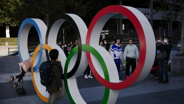 People wait in line to take pictures with the Olympic rings near the New National Stadium(AP)