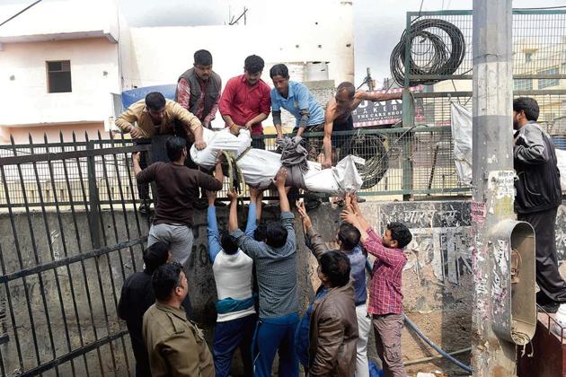 People retrieve the body of 26-year-old Ankit Sharma, an IB staffer, from a riot-affected area in north-east Delhi, on Wednesday.(Photo: PTI)