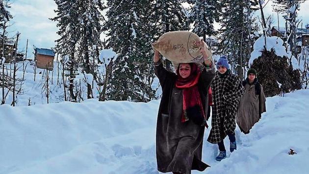 Villagers carry rice after heavy snowfall in Budgam district of Srinagar on January 18.(Photo: AFP) Villagers carry rice after heavy snowfall in Budgam district of Srinagar on January 18.(Photo: AFP)