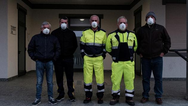 Lombardy civil protection officers wear protective masks outside the entrance of the town hall in San Fiorano. Shops are shut, the bar is closed and people speak to each other from a safe distance. (Marzio Toniolo / REUTERS)