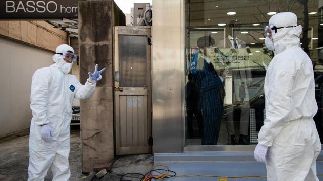 Workers wearing protective suits talk outside a clothing store on Munjeong-dong Rodeo Street in the Songpa district of Seoul, South Korea.(Bloomberg)