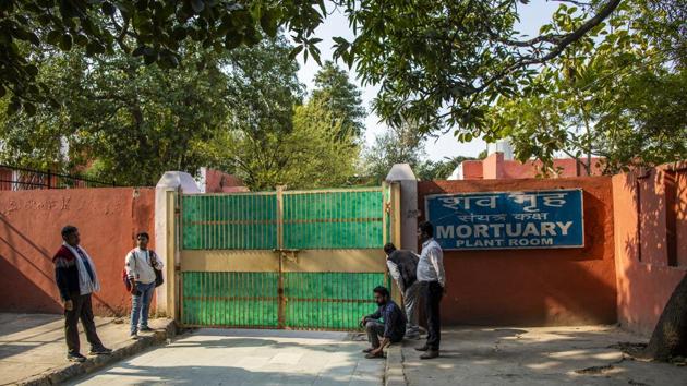 A man peeks through the gate of the mortuary to the Guru Teg Bahadur Hospital in Delhi. Some sobbed quietly in the corner and others sat catatonic with grief as bodies wrapped in white shrouds were wheeled in and out of a hospital mortuary in northeast Delhi. (Prashanth Vishwanathan / Bloomberg)