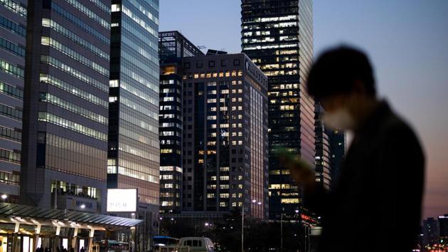 A pedestrian uses a smartphone while wearing a protective face mask in the Yeouido financial district at dusk in Seoul. (Bloomberg) A pedestrian uses a smartphone while wearing a protective face mask in the Yeouido financial district at dusk in Seoul. (Bloomberg)