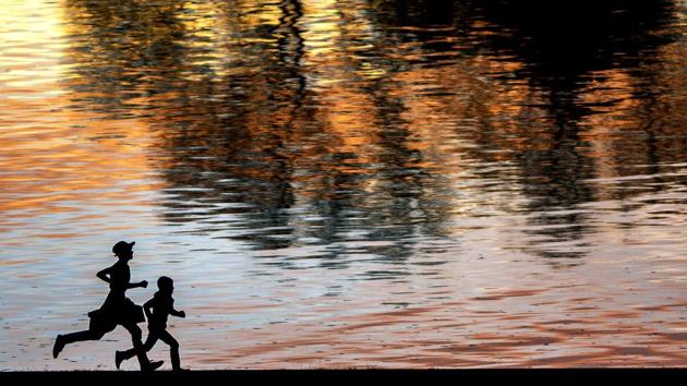 Two boys race along the Lewiston Levee Parkway Trail as the sunset shimmers on the Snake River, in Lewiston, Idaho, USA. (Pete Caster / Lewiston Tribune via AP)