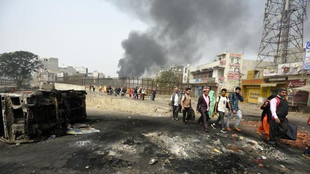 Members of a wedding procession pass through a road littered with debris and damaged vehicles while smoke rises in the background after clashes between opposing groups over the Citizenship Amendment Act (CAA) at Karawal Nagar in New Delhi. (Biplov Bhuyan / HT Photo) Members of a wedding procession pass through a road littered with debris and damaged vehicles while smoke rises in the background after clashes between opposing groups over the Citizenship Amendment Act (CAA) at Karawal Nagar in New Delhi. (Biplov Bhuyan / HT Photo)
