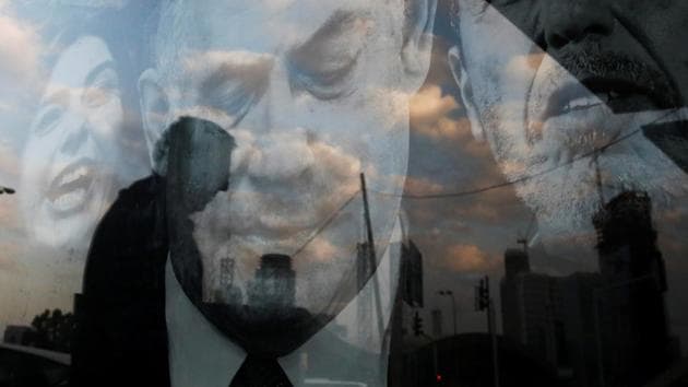 A street scene is reflected on a blue and white party election campaign poster depicting Israeli Prime Minister Benjamin Netanyahu, Minister of Culture and Sports Miri Regev and Education Minister Rafi Peretz in Tel Aviv, Israel. (Corinna Kern / REUTERS)