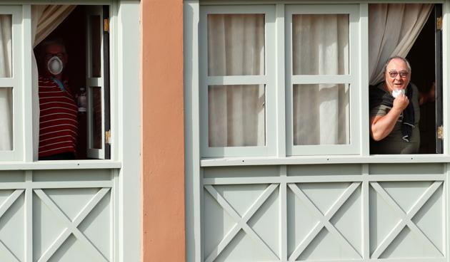 Two tourists peek out of hotel windows at H10 Costa Adeje Palace, which is on lockdown after novel coronavirus has been confirmed in Adeje, on the Spanish island of Tenerife, Spain. (Borja Suarez / REUTERS)