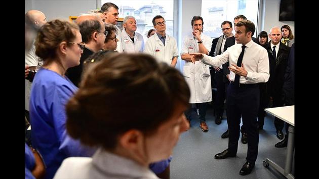 French President Emmanuel Macron flanked by French Director General of Health Jerome Salomon, meets medical staff as he visits the Pitie-Salpetriere hospital in Paris on February 27, 2020 where the first French victim of COVID-19 passed away the day before. The country has registered 57 cases so far, with 2 deaths. (Martin Bureau / AFP)