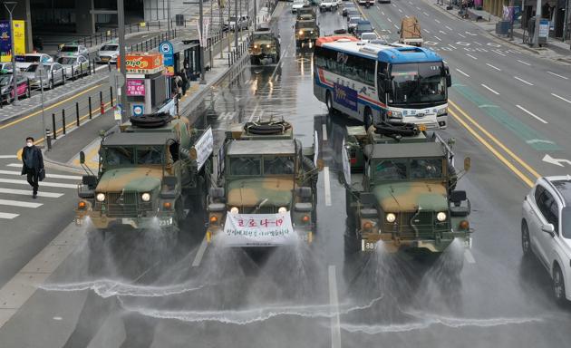 Military vehicles spray disinfectant as part of preventive measures against the spread of the COVID-19 coronavirus, on a road near Dongdaegu railway station in Daegu, South Korea. The country confirmed 594 more coronavirus cases on February 29, the biggest increase to date for the country and taking the national total to 2,931 infections with three additional deaths. (AFP)