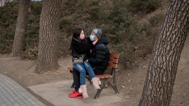 A couple wearing protective face masks, as a preventative measure against the COVID-19 coronavirus, share a romantic moment on a bench at a park in Beijing, China. The novel coronavirus has spread to more than 25 countries since it emerged in December and is causing mounting alarm due to new outbreaks in Europe, the Middle East and Asia. (Nicolas Asfouri / AFP)