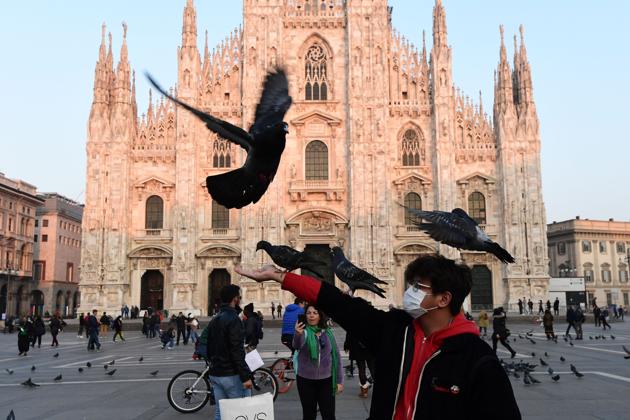 A man wearing a protective mask plays with pigeons in the Piazza del Duomo in central Milan, Italy, following security measures taken in northern Italy against the novel coronavirus. (Miguel Medina / AFP)