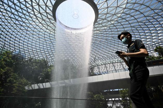 A man, wearing a protective face mask amid fears about the spread of the COVID-19 novel coronavirus, walks past the Rain Vortex display at Jewel Changi Airport in Singapore. The country has registered 98 cases of the virus so far. (Roslan Rahman / AFP)