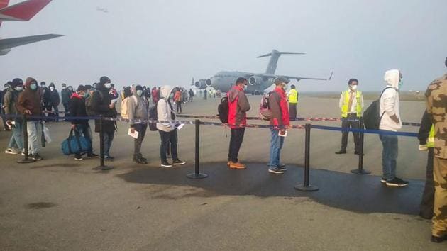 Indian nationals and foreigners stand in a queue after they were brought to India by an Indian Air Force's (IAF) C-17 Globemaster III aircraft from China's coronavirus-hit city of Wuhan, at airport in New Delhi.(PTI)