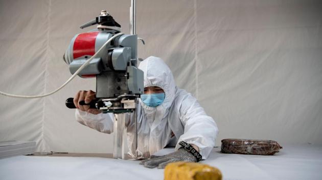 A worker cuts fabric for the production of hazardous material suits. The company in the eastern China export hub of Wenzhou hastily repurposed its assembly line, putting the few dozen workers it could muster to produce thousands of single-use protective suits daily. (Noel Celis / AFP) A worker cuts fabric for the production of hazardous material suits. The company in the eastern China export hub of Wenzhou hastily repurposed its assembly line, putting the few dozen workers it could muster to produce thousands of single-use protective suits daily. (Noel Celis / AFP)