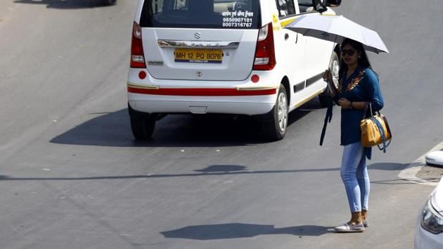 A woman takes shade under an umbrella on a sunny day.(Rahul Raut/HT PHOTO)