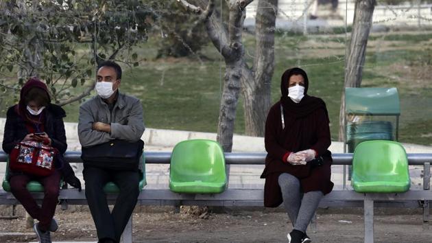 People wearing face masks wait for bus in a bus stop in a street in western Tehran, Iran. Iran has asked India to evacuate its citizens from the country as it prepares to face a coronavirus outbreak.(AP)