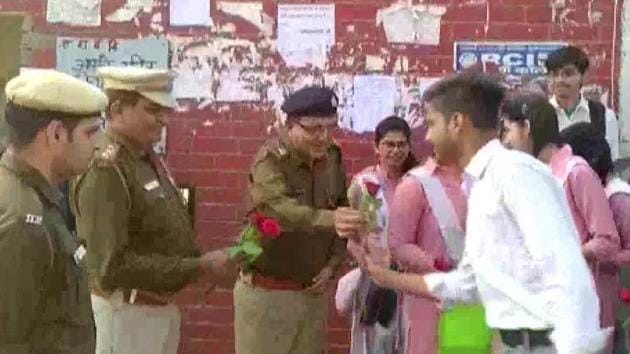 Delhi Police personnel distribute roses to students who have come to Sarvodaya Vidyalaya in Khajoori Khas area of Northeast Delhi on Monday for their exams. (ANI Photo) Delhi Police personnel distribute roses to students who have come to Sarvodaya Vidyalaya in Khajoori Khas area of Northeast Delhi on Monday for their exams. (ANI Photo)
