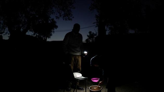 Hosini and his wife Yasamin wake up before dawn and enter Moria, taking turns to wait in line for three hours to receive meals. The food is not enough for the family of five, so they cook for themselves on a stove made from an empty can filled with charcoal and wood. (Alkis Konstantinidis / REUTERS) Hosini and his wife Yasamin wake up before dawn and enter Moria, taking turns to wait in line for three hours to receive meals. The food is not enough for the family of five, so they cook for themselves on a stove made from an empty can filled with charcoal and wood. (Alkis Konstantinidis / REUTERS)