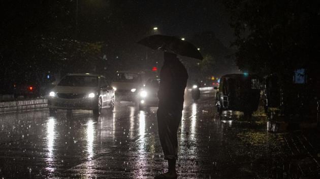 A man holds an umbrella as vehicles ply during rainfall in New Delhi. (PTI) A man holds an umbrella as vehicles ply during rainfall in New Delhi. (PTI)