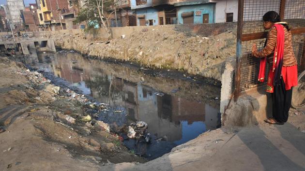 A passerby looks at a body lying in a drain in Brahampuri on February 27. (Amal KS / HT Photo)