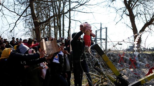 Migrants wait at the Turkey’s Pazarkule border crossing. Hamid Muhammed, who carried a young girl, said he was turned away by Greek police. “We want the Turkish and European governments to open this gate,” he said. (Osman Sadi Temizel / REUTERS) Migrants wait at the Turkey’s Pazarkule border crossing. Hamid Muhammed, who carried a young girl, said he was turned away by Greek police. “We want the Turkish and European governments to open this gate,” he said. (Osman Sadi Temizel / REUTERS)