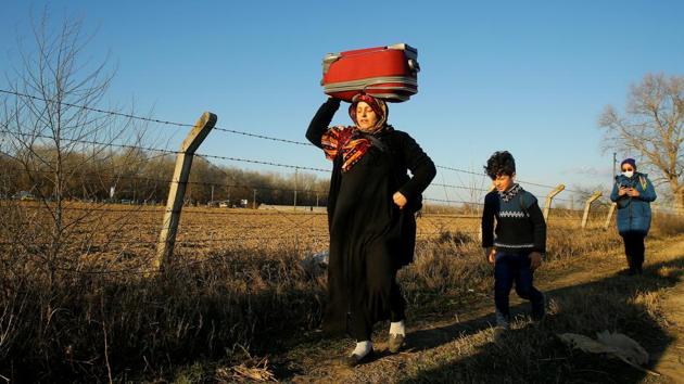 A woman carries a luggage on her head as she walks with a child to the Turkey’s Pazarkule border crossing with Greece’s Kastanies. Moscow and Ankara traded blame over Thursday’s strike in northwest Syria, the deadliest attack on Turkish forces in nearly 30 years. The UN Security Council called an emergency meeting to avert open conflict between Russia and NATO member Turkey. (Huseyin Aldemir / REUTERS) A woman carries a luggage on her head as she walks with a child to the Turkey’s Pazarkule border crossing with Greece’s Kastanies. Moscow and Ankara traded blame over Thursday’s strike in northwest Syria, the deadliest attack on Turkish forces in nearly 30 years. The UN Security Council called an emergency meeting to avert open conflict between Russia and NATO member Turkey. (Huseyin Aldemir / REUTERS)