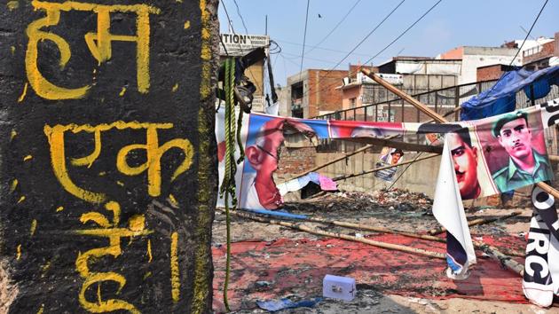 A slogan reads “We are one” as banners bearing the faces of India’s freedom fighters are seen damaged in the background following the clashes at Mustafabad on February 26. (Raj K Raj / HT Photo)