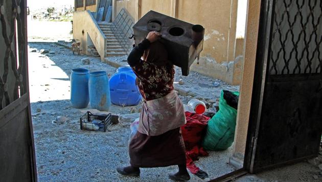 A displaced Syrian woman collects belongings from a school that was reportedly targeted in a regime forces' air strike in Syria's northwestern Idlib province.(AFP)