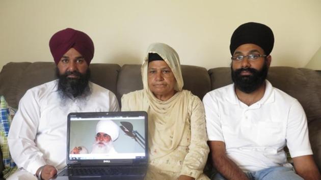 Raghuvinder Singh (left) and Jaspreet Singh, with their mother Kulwant Kaur and a photograph of their father Baba Punjab Singh at their house in Oak Creek, Wisconsin.(AP Photo)