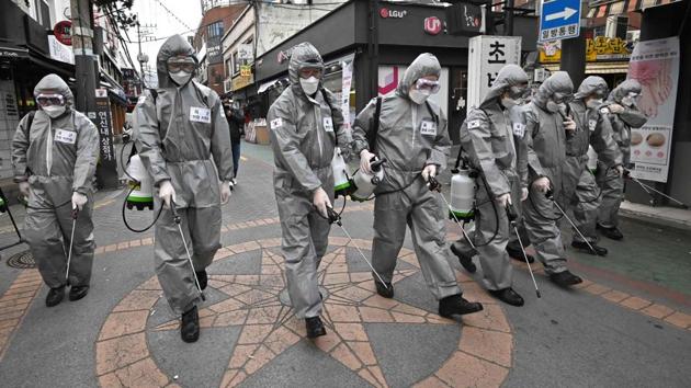 South Korean soldiers wearing protective gear spray disinfectant to help prevent the spread of the Covid-19 coronavirus, at a shopping district in Seoul on March 4.(AFP Photo)