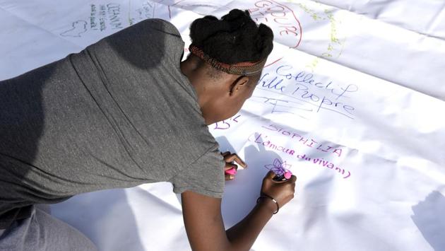 A volunteer signs a poster during the clean-up operation. El Hadj Abdoulaye Seck, a dual French-Senegalese national on holiday in Dakar, was one of the people scouring the sands. “This project is of capital importance,” he said with a smile, adding every citizen’s duty was to “participate in the development of our country.”  (Seyllou / AFP) 